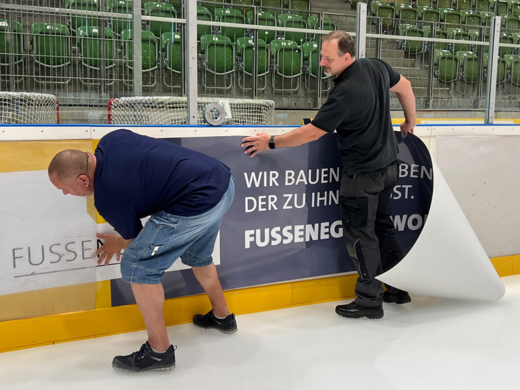 bande fussenegger Mit Hilfe der beiden Eismeister zog die Fussenegger Wohnbau GmbH über die neue Bandenwerbung in die CHG Arena ein. Bild: Fussenegger Wohnbau GmbH